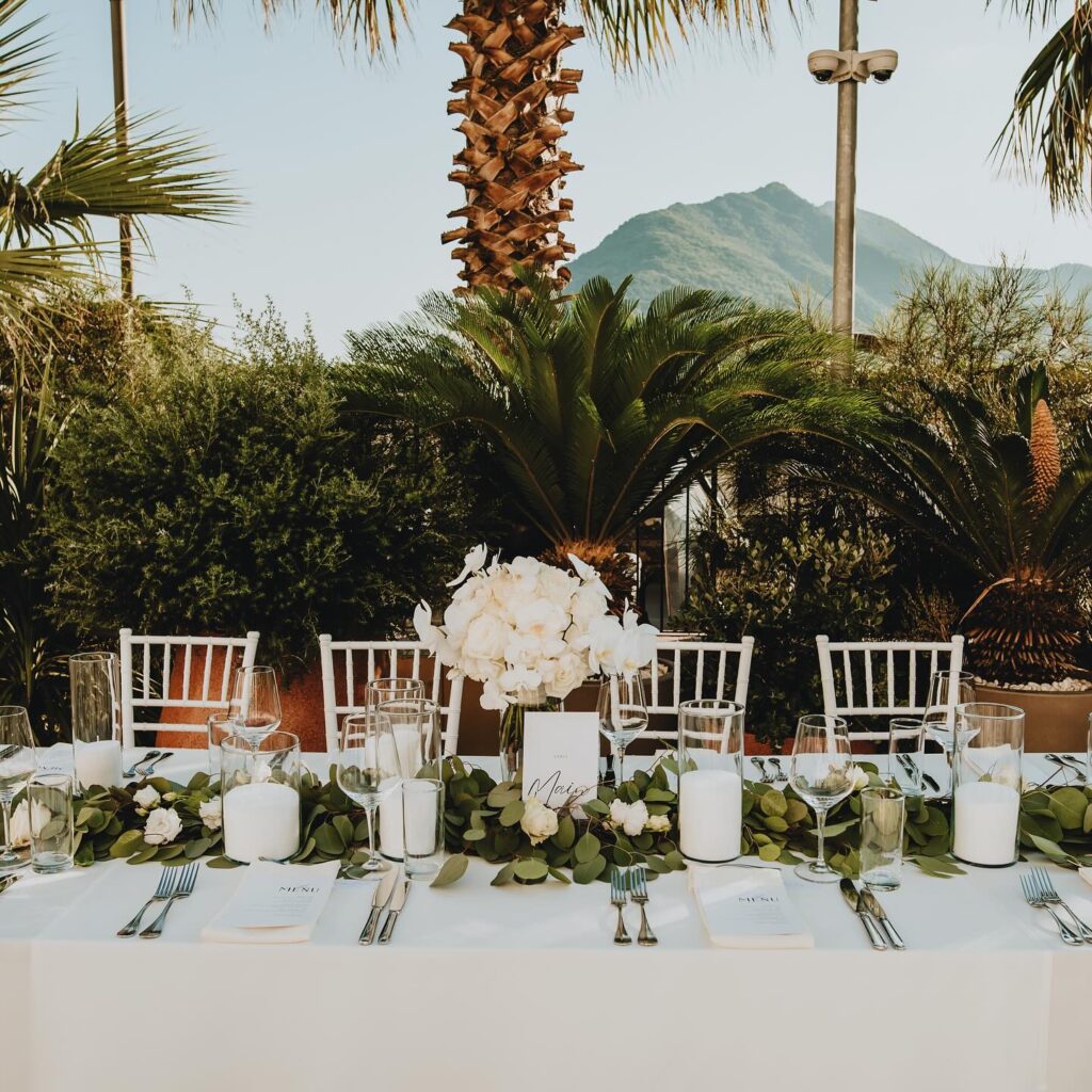 Wedding table styling with white florals in the garden at Grand Heritage Perast, with Bay of Kotor mountains behind.