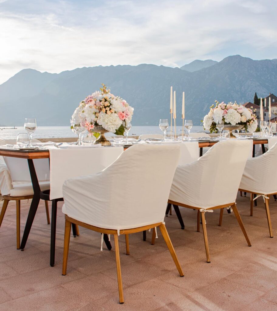 Outdoor wedding dining setup on a terrace in Perast with Bay of Kotor views and floral centrepieces.