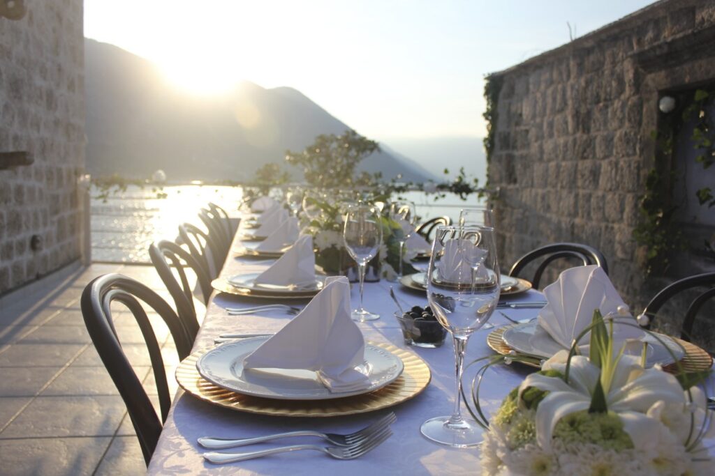 Sunset dinner table set on a stone terrace overlooking Kotor Bay at Palazzo Radomiri in Dobrota, Montenegro.