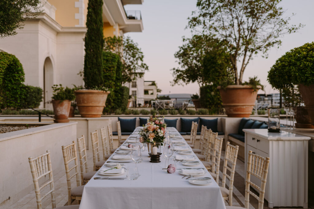Long wedding dinner table set outdoors in Regent Porto Montenegro’s Italian Garden at sunset.