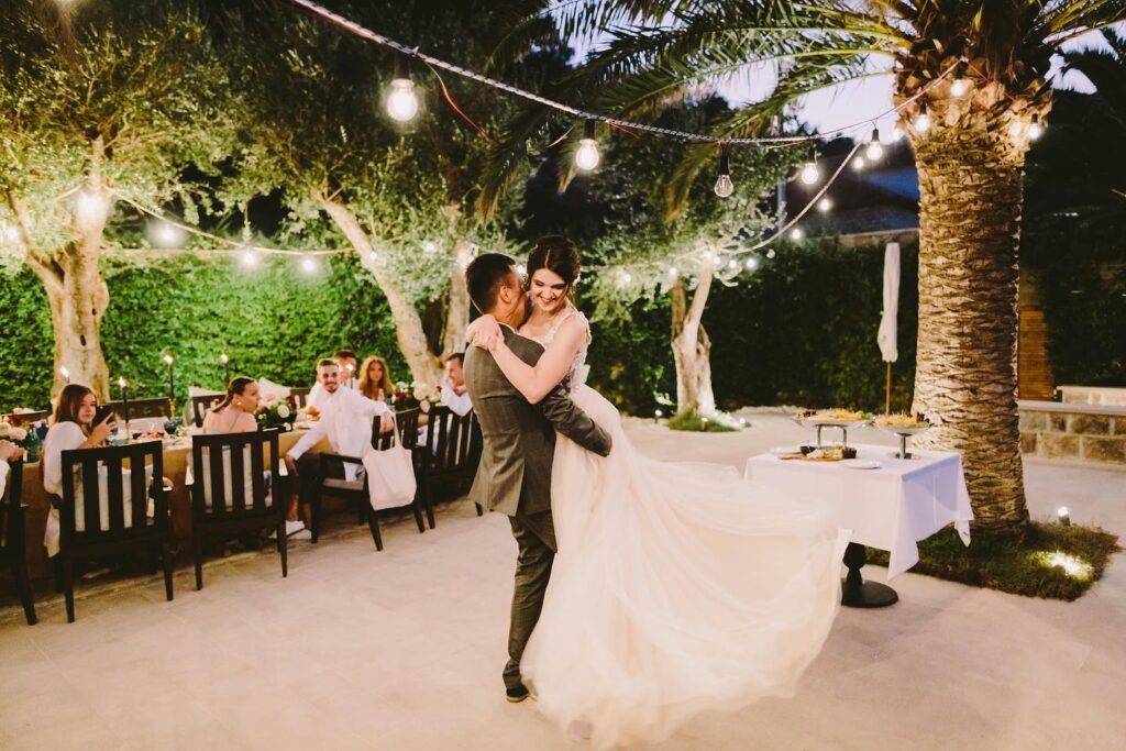 Bride and groom first dance under string lights at Adriatica Restaurant & Beach Club, Boka Bay, Montenegro.