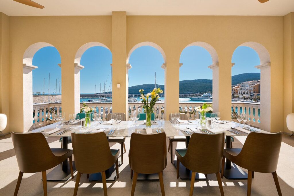 Arched terrace set for dining overlooking the marina at The Chedi Luštica Bay, Montenegro. Caption: Terrace dining with Luštica Bay marina views.