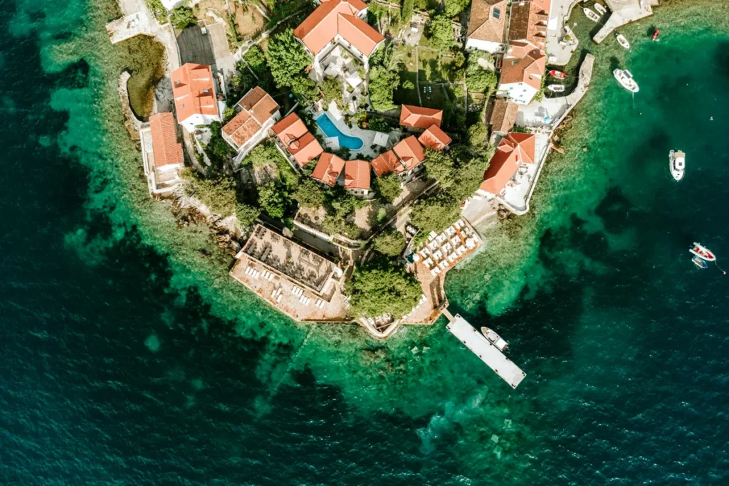Aerial view of Forte Rose waterfront complex with pier and turquoise sea in Rose, Luštica Peninsula, Montenegro.