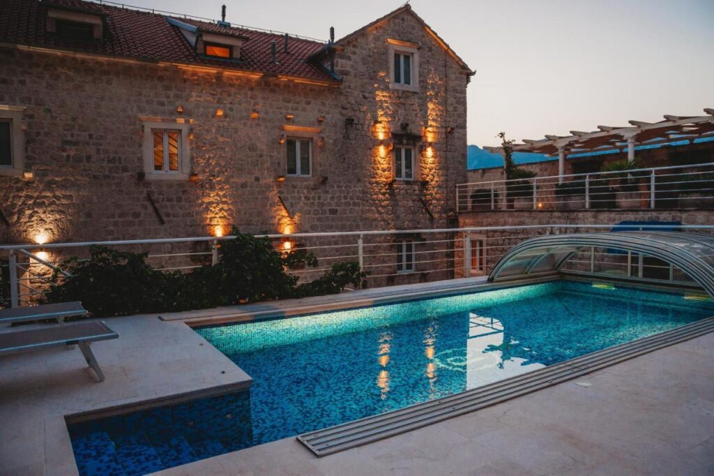 Evening view of Palazzo Radomiri stone façade and outdoor pool in Dobrota on Kotor Bay, Montenegro.